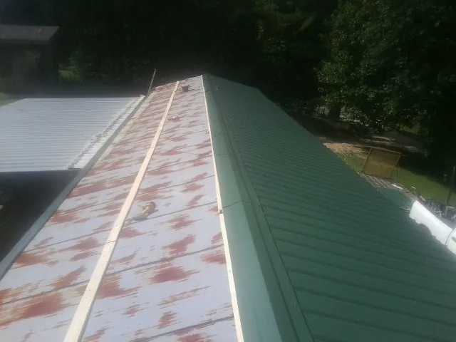 Old rusted panels beside newly installed green metal roofing — Wind Damage Roof Repair by Roofing Brothers in Meriden
