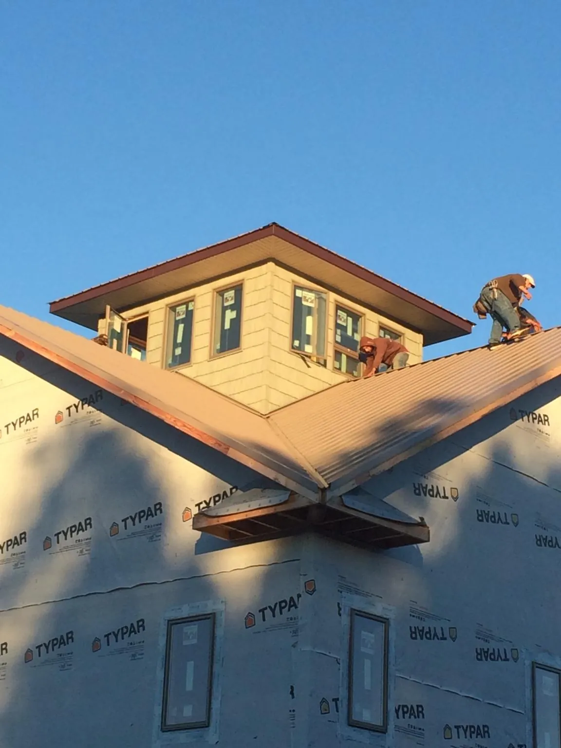 Roofers working around a rooftop cupola on a new metal roof at sunset — Roof Waterproofing in Meriden by Roofing Brothers